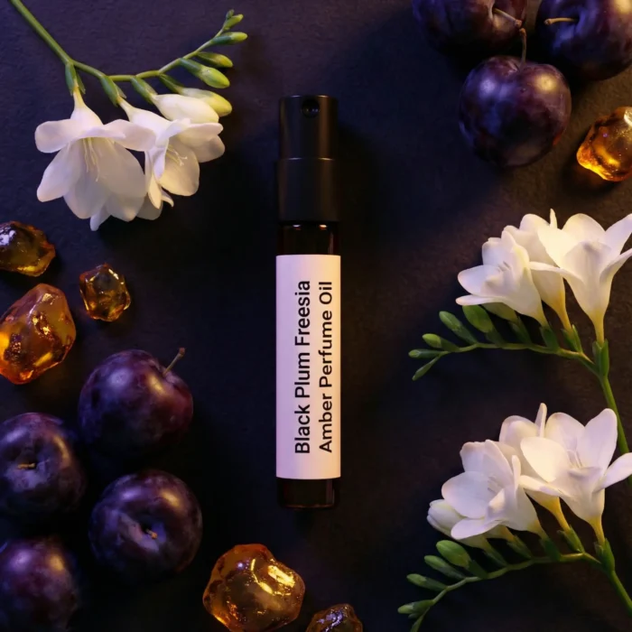 Black Plum Freesia Amber perfume oil bottle with dark plums, freesia flowers and glowing amber crystals under night lighting.