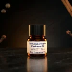 Oud amber spice perfume oil background with dark smoky oud wood, glowing amber resin and warm oriental spice atmosphere.